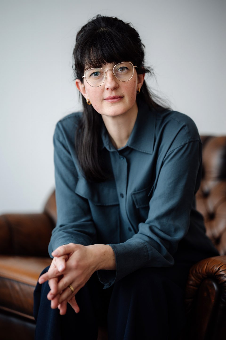 Porträt von Nora Urgatz, sitzend auf einem Ledersofa